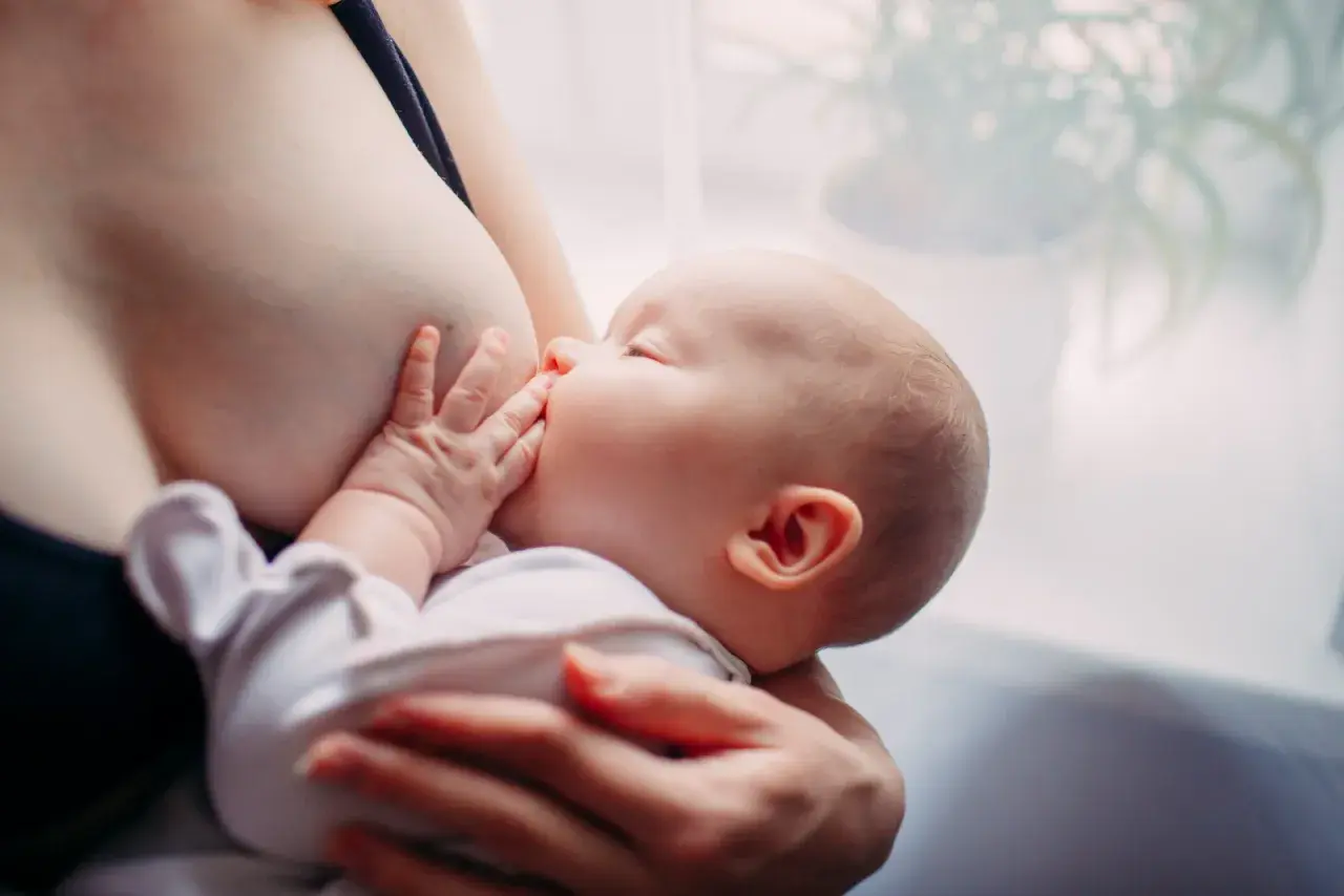 Un neonato si nutre al seno. Scopri come aumentare il latte materno in modo naturale per il benessere del tuo bambino.