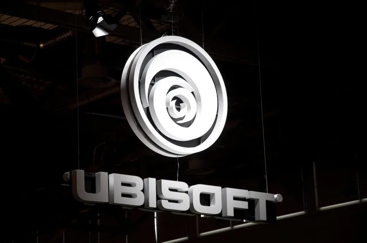 Jasne, oto opis alternatywny:

Podświetlone logo Ubisoft i nazwa firmy wiszą w ciemnym pomieszczeniu. To świetna reklama dla fanów gier Ubisoft akcje.