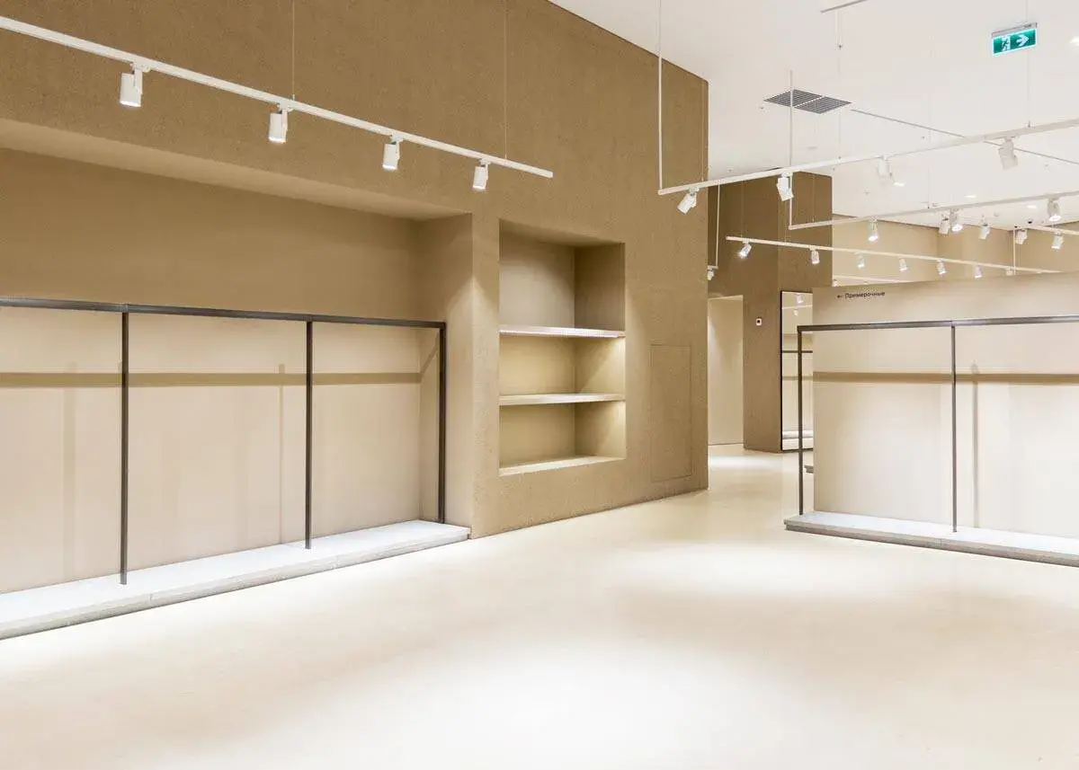 Interni di un locale commerciale in fase di ristrutturazione, con scaffalature vuote e illuminazione a faretti.