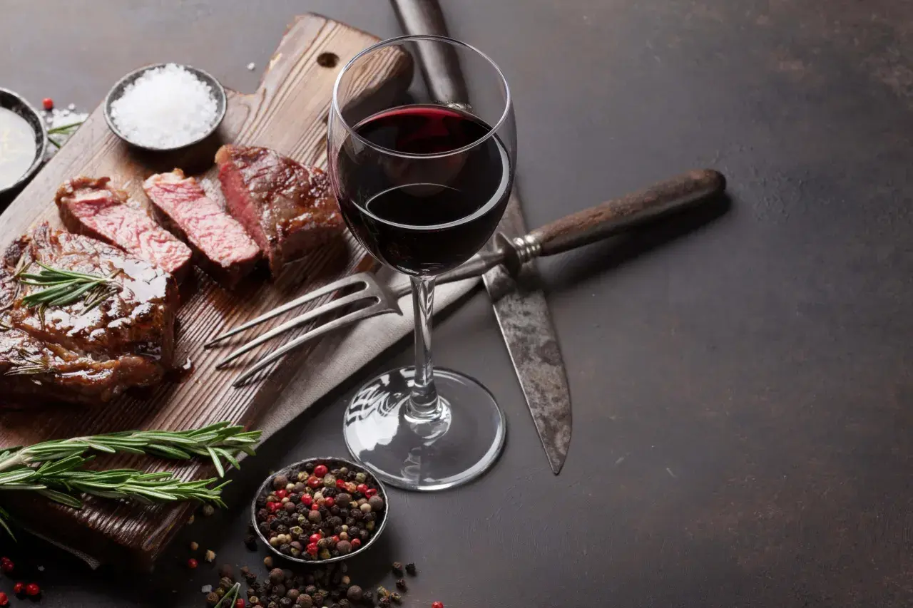 Un verre de vin malbec, parfait pour accompagner ce steak juteux. Une dégustation qui évoque la richesse d'une belle région viticole.