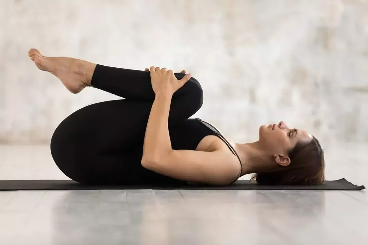 Mujer en postura de yoga para aliviar gases. Si sufres de gases, esta postura puede ser una ayuda natural.