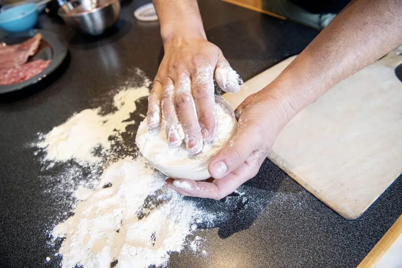 Händer som knådar deg med mjöl för en äkta neapel pizza.