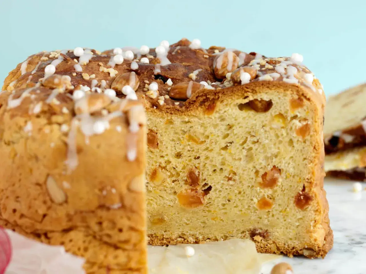 En skiva av ett gyllene panettone, dekorerad med mandlar och glasyr. Detta är ett recept på original panettone.
