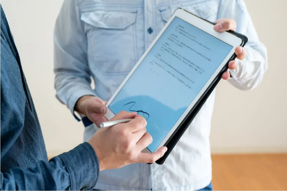 Firma electrónica en tablet, un hombre firma un documento digital con un stylus. El acto tiene pleno p.p. significado jurídico.