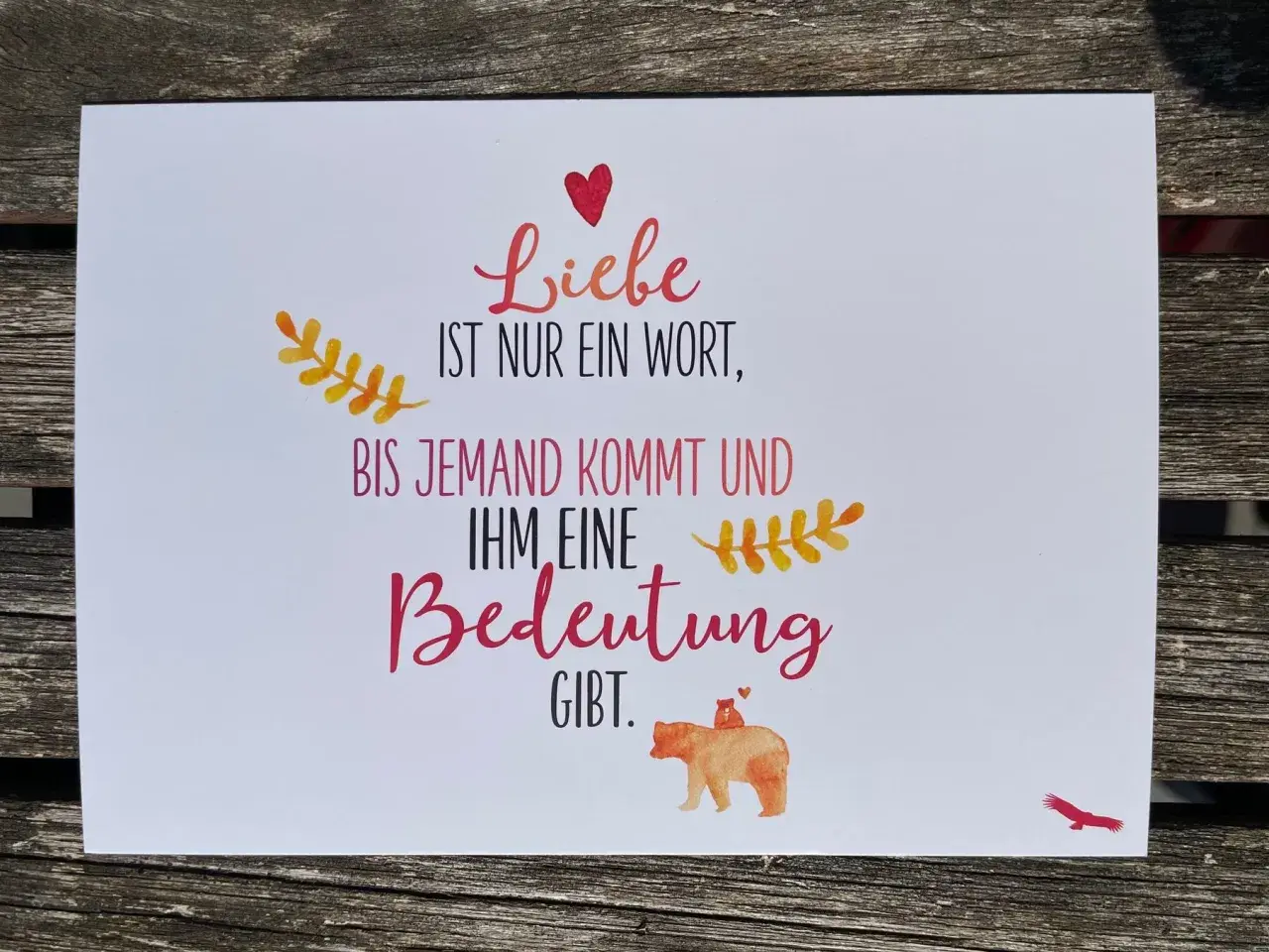 Eine Karte mit der Aufschrift "Liebe ist nur ein Wort, bis jemand kommt und ihm eine Bedeutung gibt." Ein Bärenbaby sitzt auf dem Rücken eines Bären.