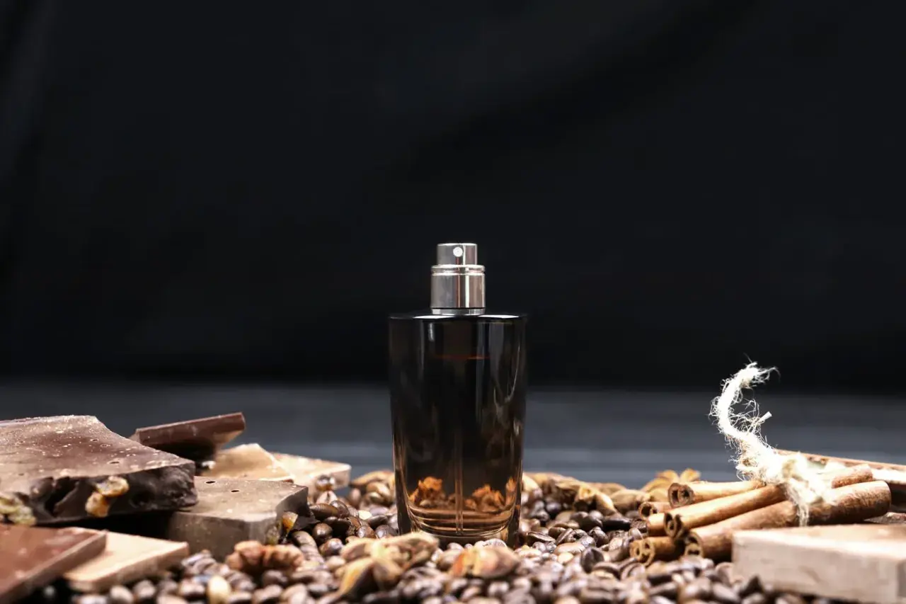 Męskie perfumy arabskie w ciemnej butelce, otoczone czekoladą, kawą i cynamonem.