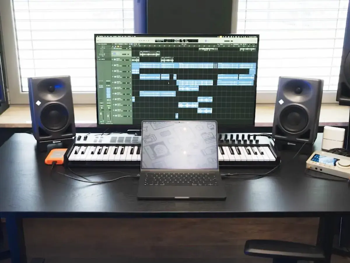 Studio do nagrywania muzyki: monitory studyjne, klawiatury MIDI, laptop i ekran z sekwencerem.