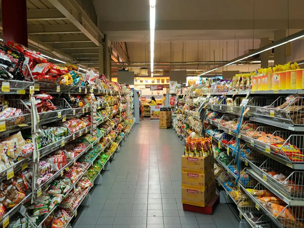 Długie alejki pełne kolorowych opakowań, typowe dla **Holandii sklepy** spożywcze. Widać mnóstwo przekąsek, słodyczy i produktów instant.