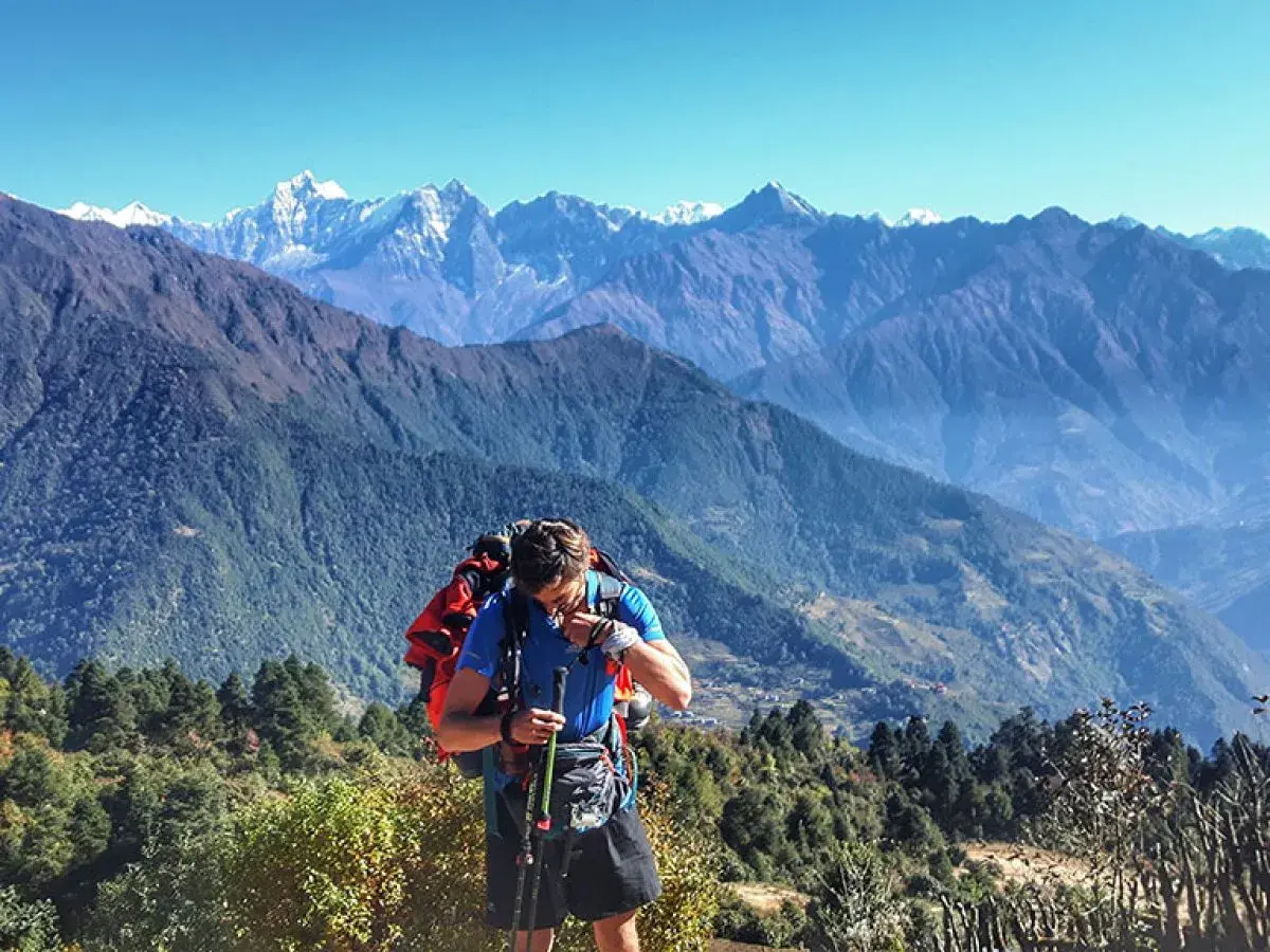 Mężczyzna z plecakiem i kijkami podczas trekking w himalajach. Majestatyczne góry w tle.