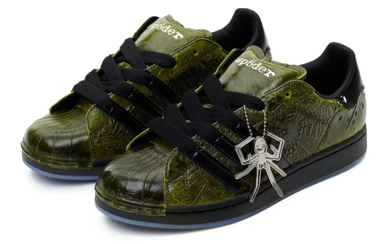 Grüne Adidas Superstar Sneaker mit Spinnennetz-Muster und Spinnen-Anhänger. Ein Highlight der Adidas Kollaborationen.