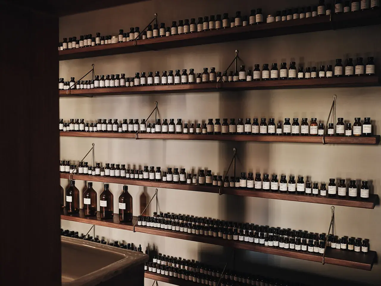 Wiele buteleczek z perfumami na drewnianych półkach. Idealne miejsce, gdzie trzymać perfumy, by były zawsze pod ręką.