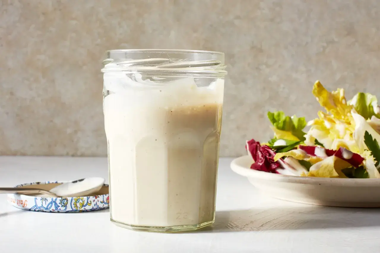 A jar of creamy miso dressing sits next to a fresh salad, ready to add a savory umami kick.