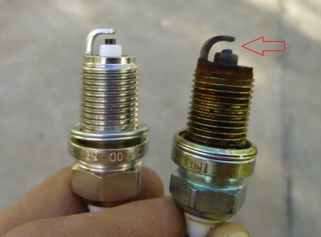 Una bujía nueva y otra desgastada, con óxido y el electrodo doblado. Así puedes saber si las bujías están mal.