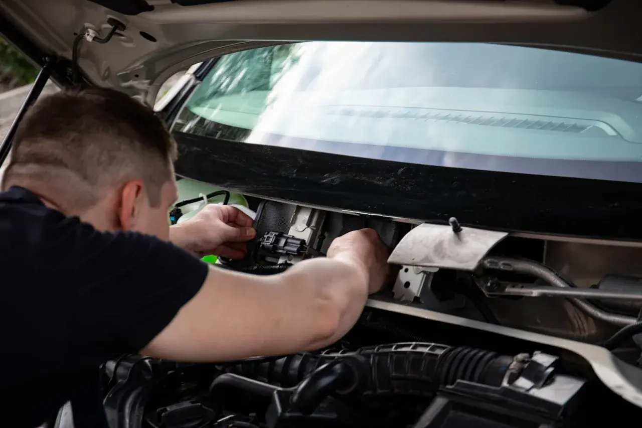Mechanik sprawdza wiązkę w samochodzie, podłączając złącze elektryczne w komorze silnika.