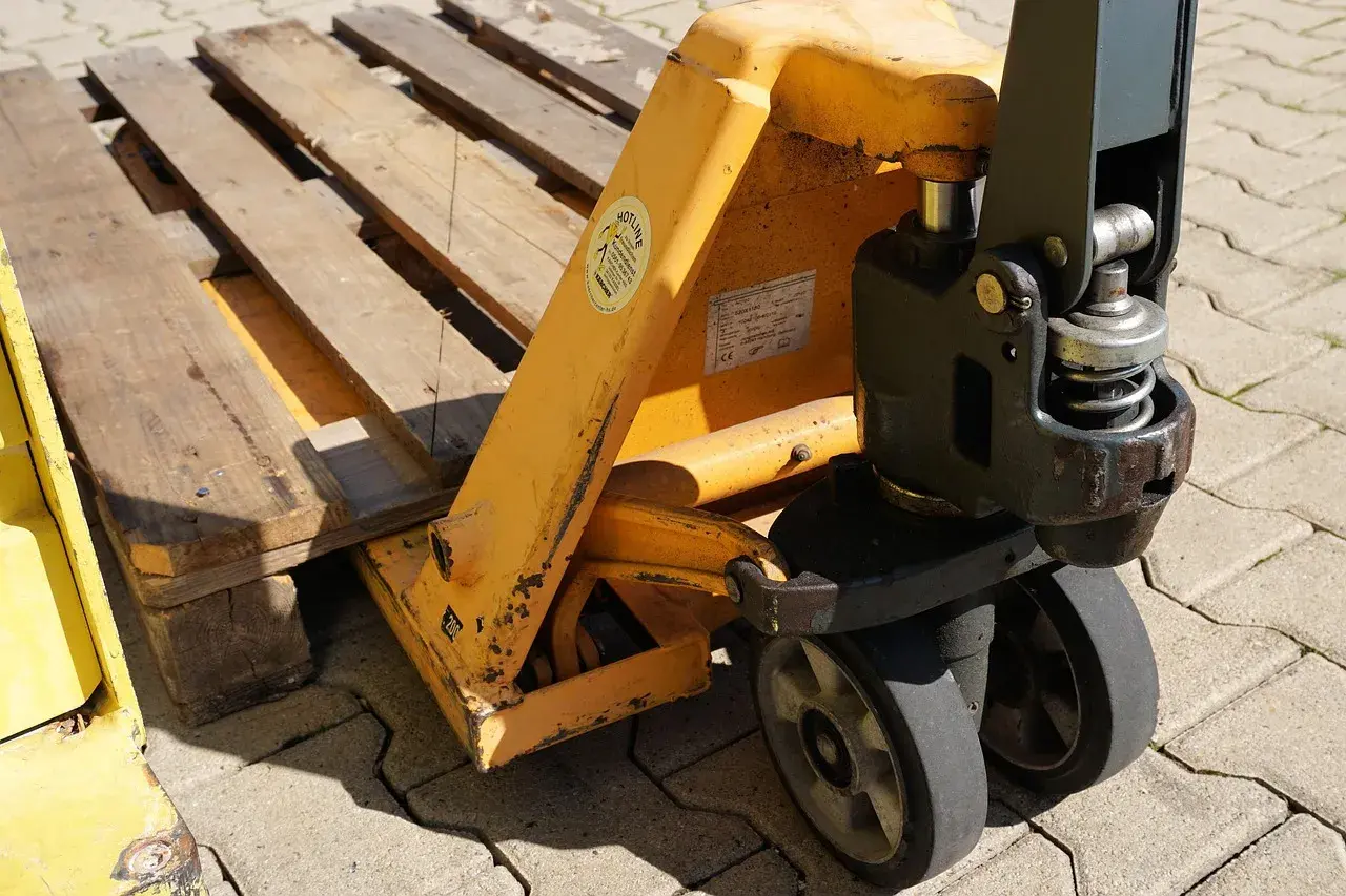 Ein Hubwagen hebt eine Holzpalette an. Dies ist ein gängiges Werkzeug im Lager, um Waren zu bewegen.