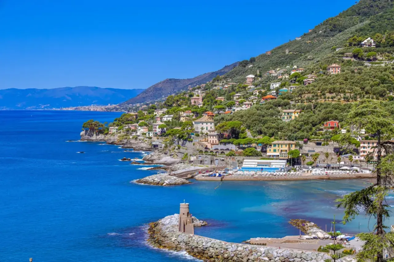 Vue pittoresque de la Riviera Italienne, avec des maisons colorées nichées sur une colline verdoyante surplombant la mer bleue.
