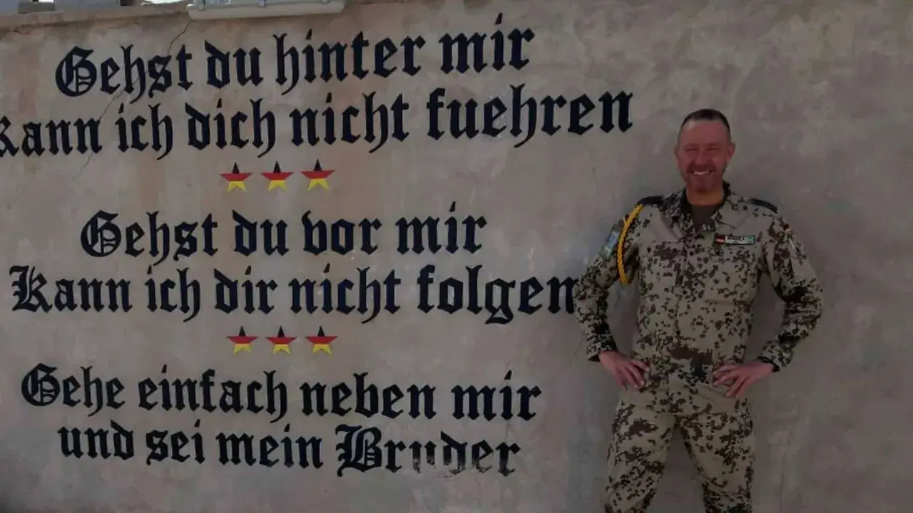Ein Soldat der Bundeswehr steht vor einer Wand mit inspirierenden Bundeswehr Zitaten. "Gehe einfach neben mir und sei mein Bruder.