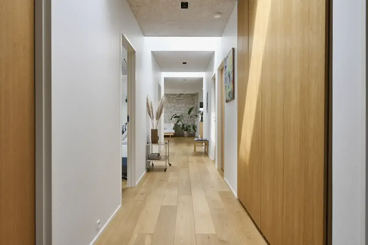 Un luminoso vano di disimpegno con pavimenti in legno chiaro, pareti bianche e armadi in legno.