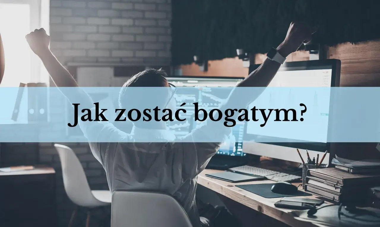 Mężczyzna z rękami w górze siedzi przy biurku z komputerem, na którym widać wykresy.