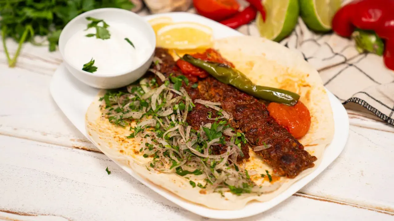 Domowy kebab z mięsem, cebulą, pietruszką, pomidorami i sosem jogurtowym na placku.