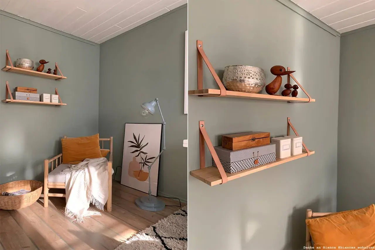Beruhigende wandfarbe im arbeitszimmer mit Holzregalen, die mit Deko und Boxen bestückt sind. Ein Sessel mit Kissen und Decke lädt zum Verweilen ein.