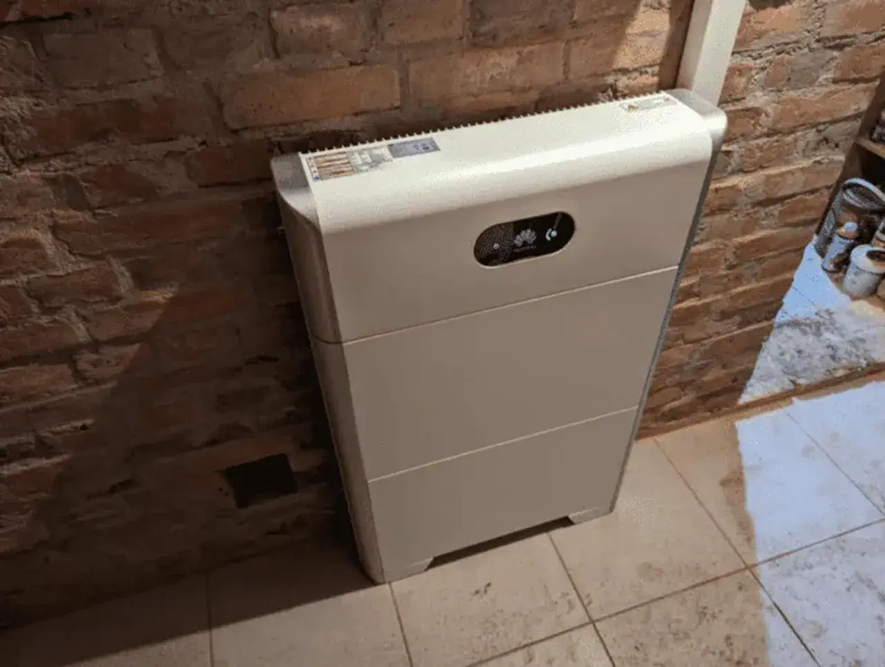Biały magazyn energii 10kW, stojący przy ceglanej ścianie, to serce domowej instalacji fotowoltaicznej. Zastanawiasz się, na ile wystarczy energii z takiego magazynu?