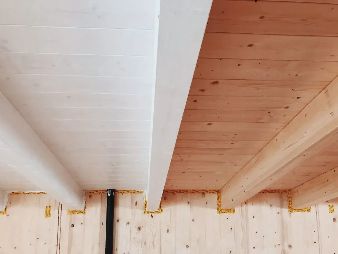 Soffitto con perline in legno sbiancato e travi a vista in legno naturale.