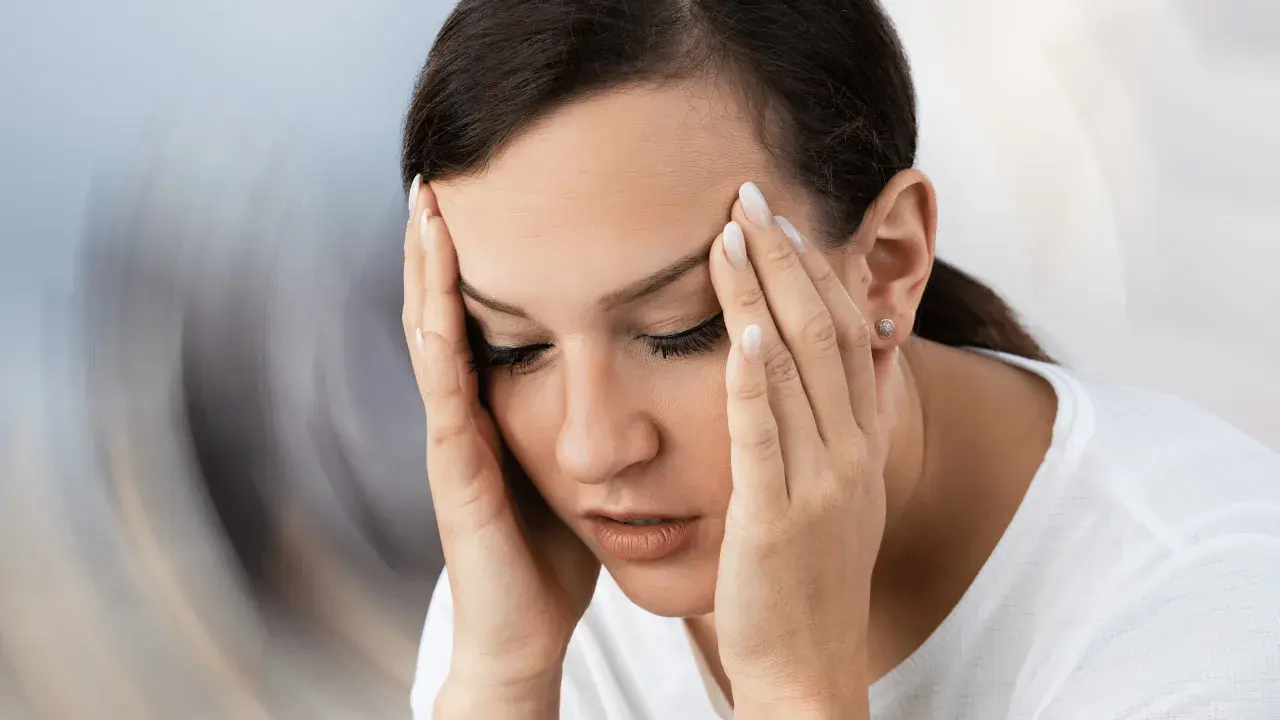 Kobieta z dłońmi na skroniach, cierpiąca na zawroty głowy, być może potrzebuje leku jak Betaserc.