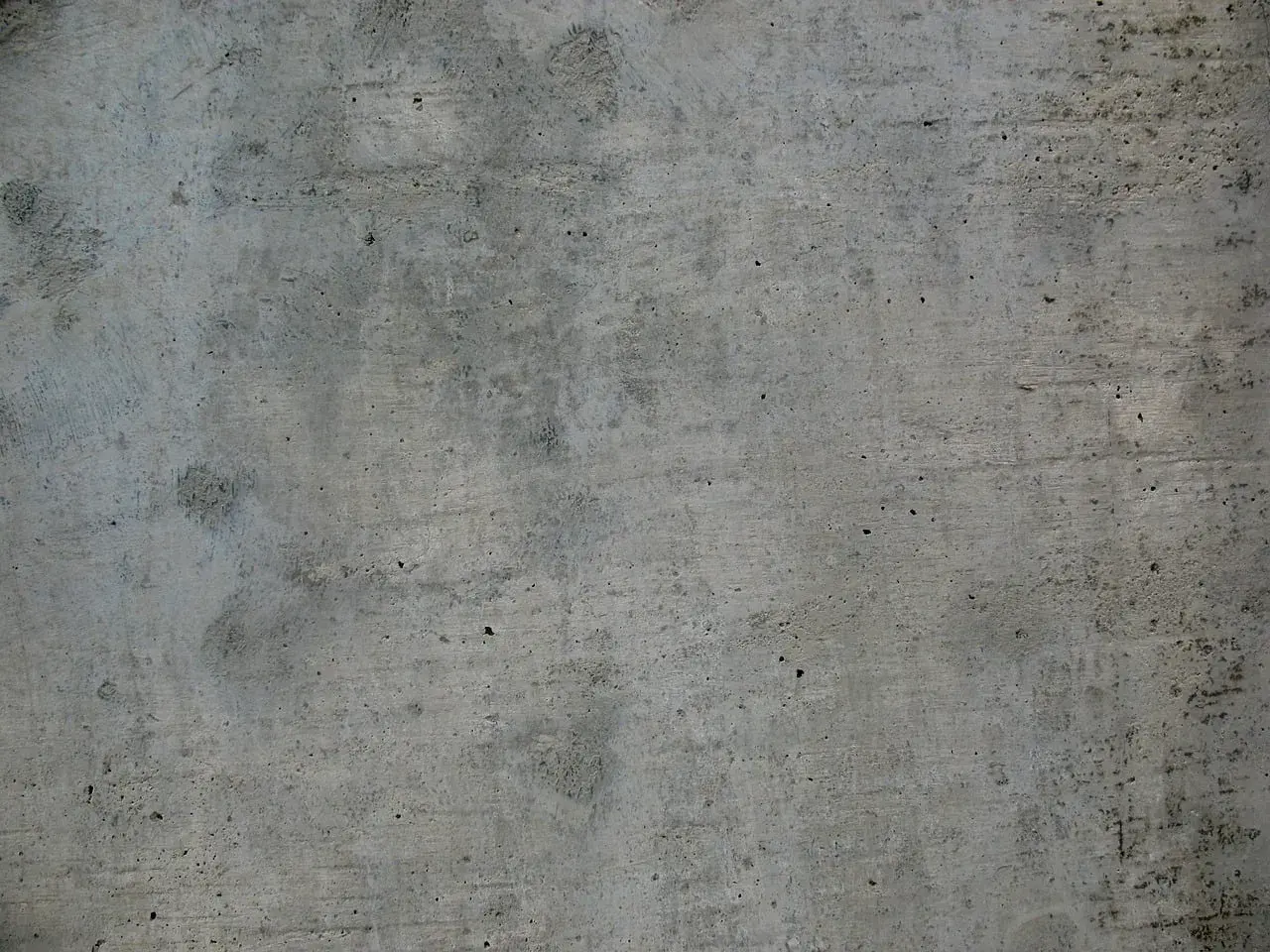 Szara, chropowata powierzchnia betonu z widocznymi nierównościami i śladami po szalunku.