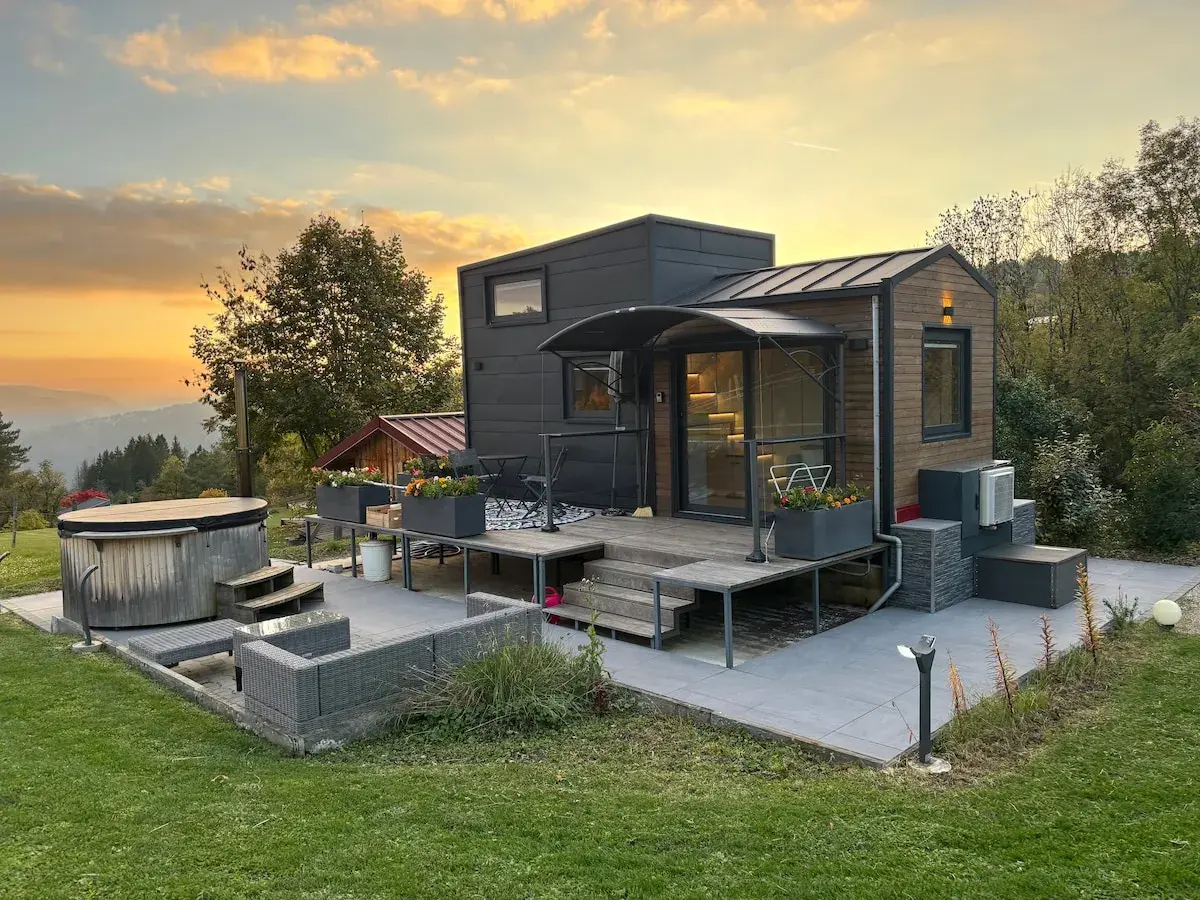 Tiny house dans le Jura, avec jacuzzi et mobilier extérieur, au coucher du soleil.