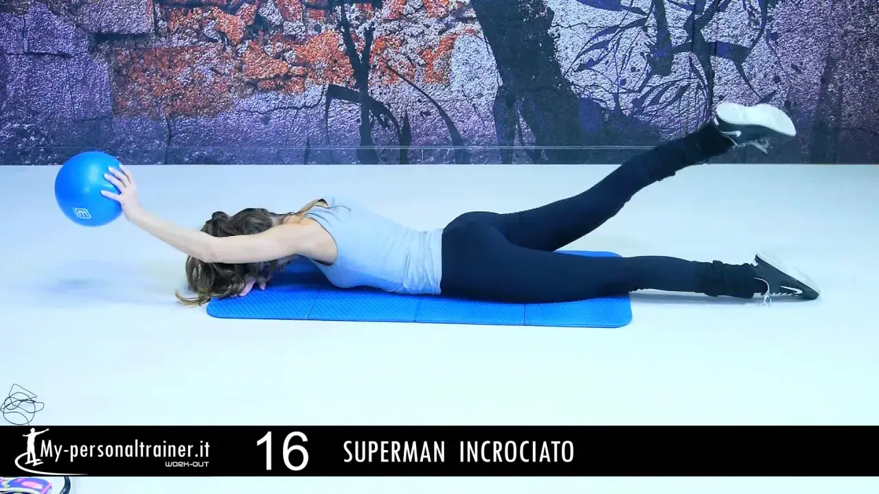 Donna esegue esercizio "Superman incrociato" per rafforzare i lombari muscoli, sollevando una gamba e un braccio con una palla blu.