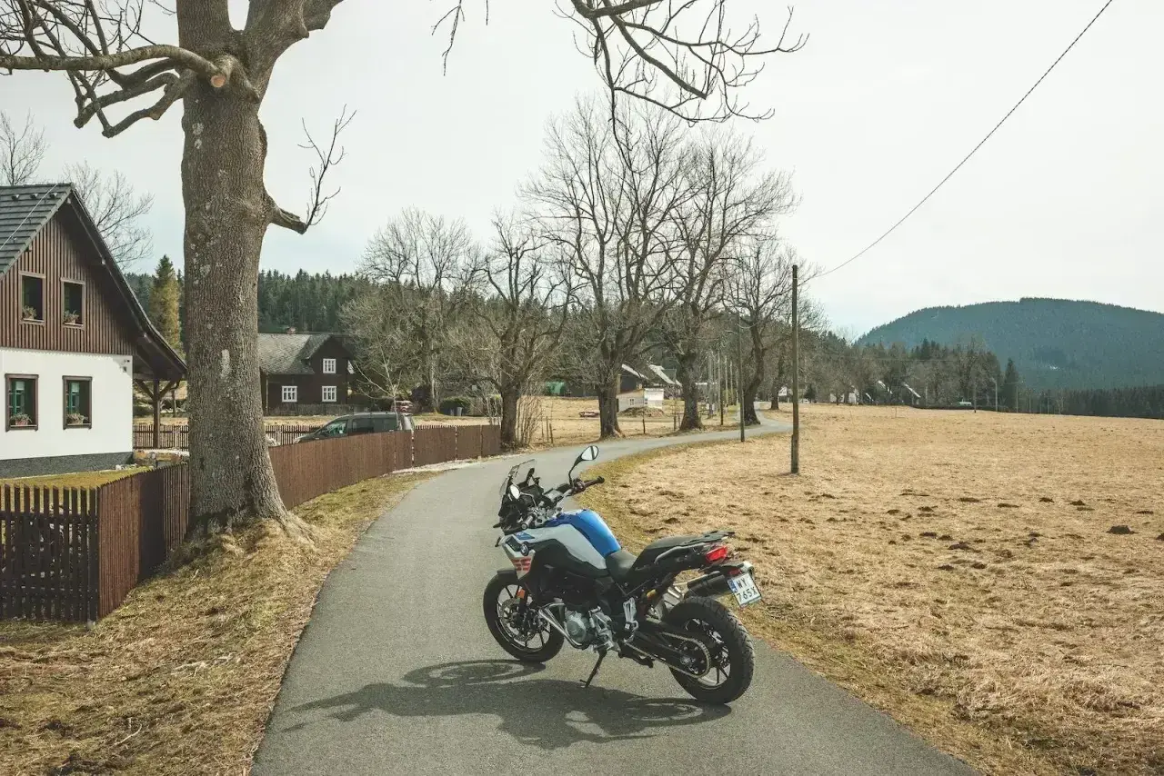 Motocykl na drodze w Czechach, wśród domków i drzew.