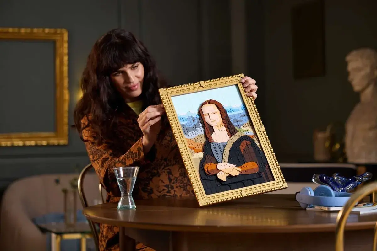 Frau hält ein detailreiches Lego-Mona-Lisa-Bild hoch.
