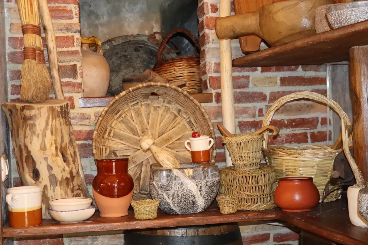 Vasi in terracotta, cesti intrecciati e scope di paglia evocano antiche attività artigianali.