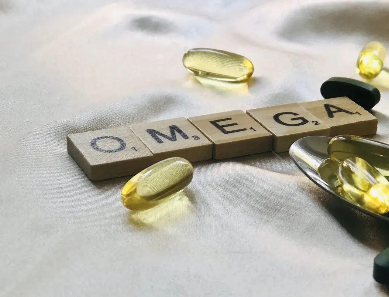 Capsule di olio di pesce e tessere con la scritta OMEGA. Chissà dopo quanto tempo fanno effetto gli omega-3 per il benessere.