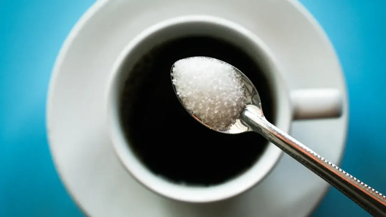Cuillère de sucre au-dessus d'une tasse de café noir. Une image pour illustrer l'arrêter le sucre effet.