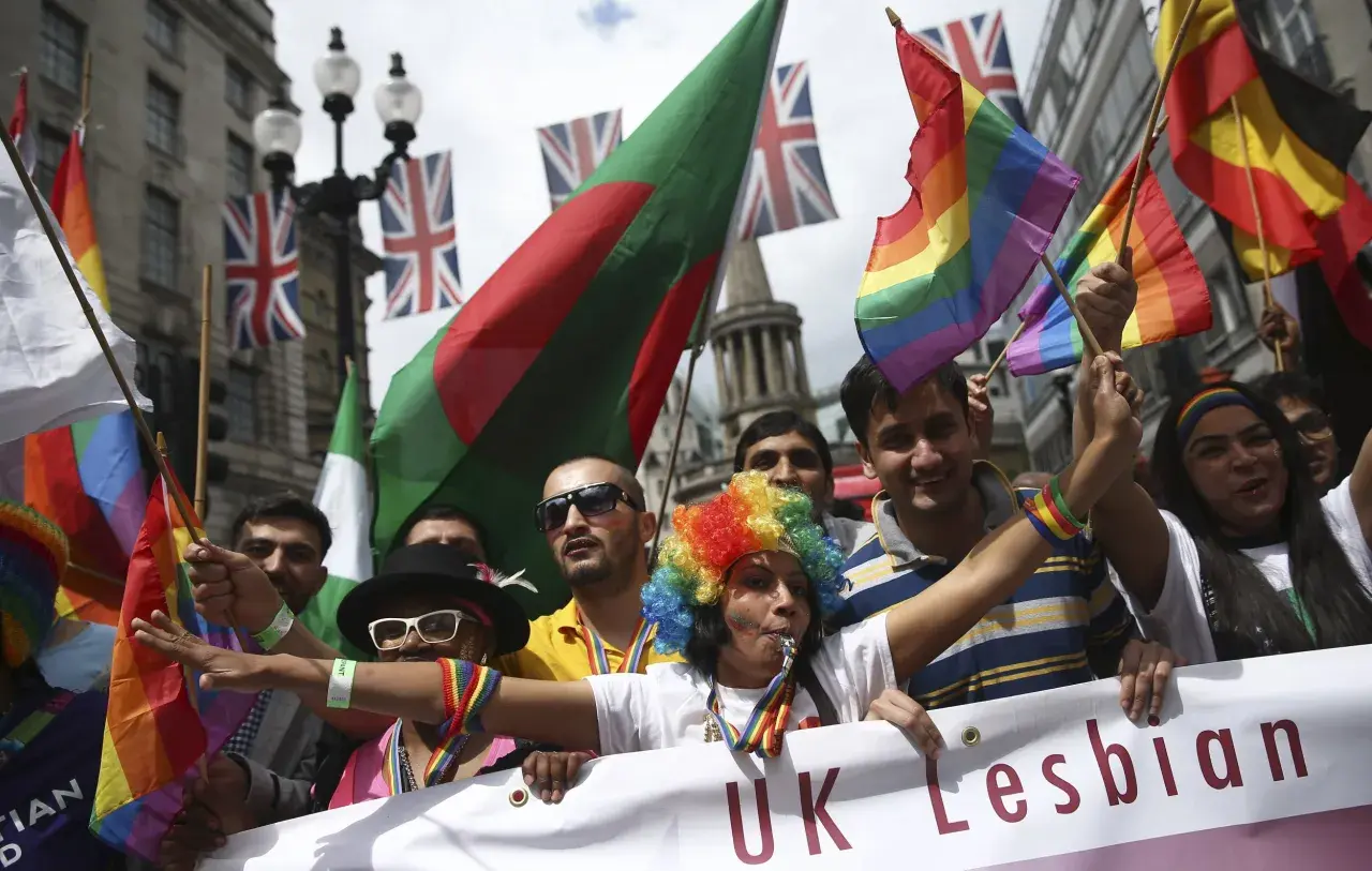 People wave rainbow and national flags at a pride parade, showing why understanding diversity is important for unity and celebration.