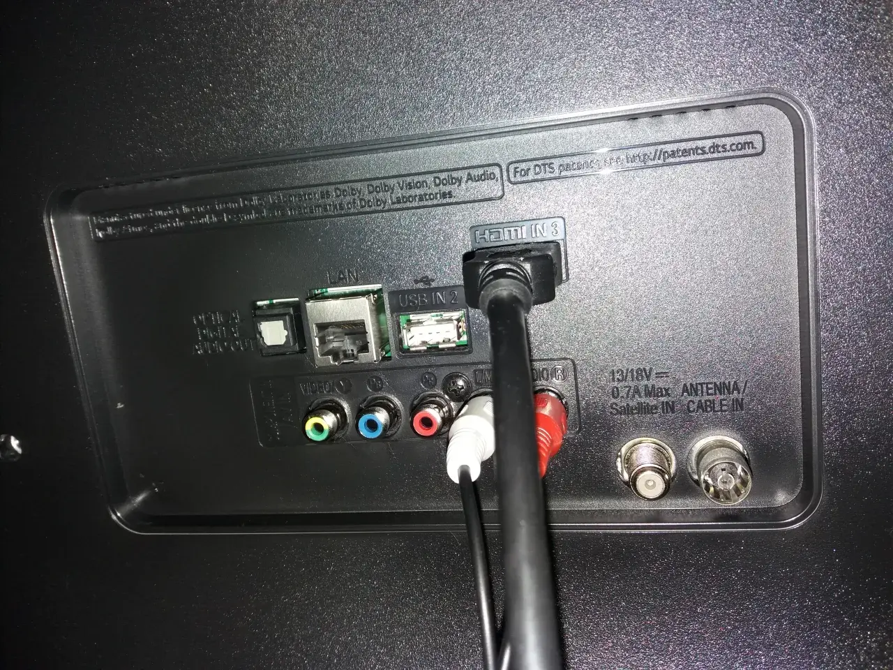 Tył telewizora z podłączonymi kablami HDMI, USB, LAN i audio.