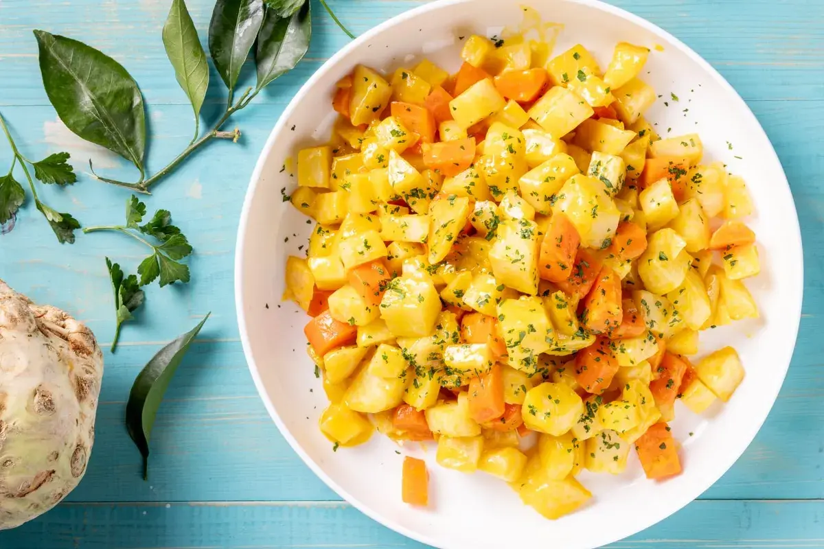 Insalata di sedano rapa e carote a cubetti, condita con erbe aromatiche. Un'idea fresca per le tue ricette crudiste.