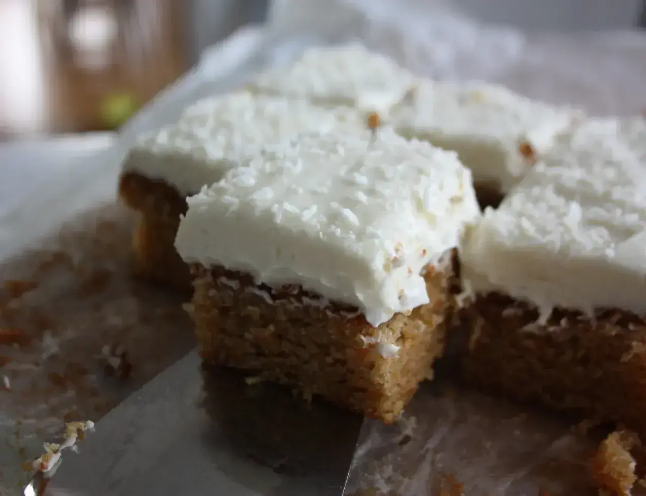 Små fyrkantiga kakor med vit frosting och kokosflingor. Kanske en hint av lime curd i smaken?