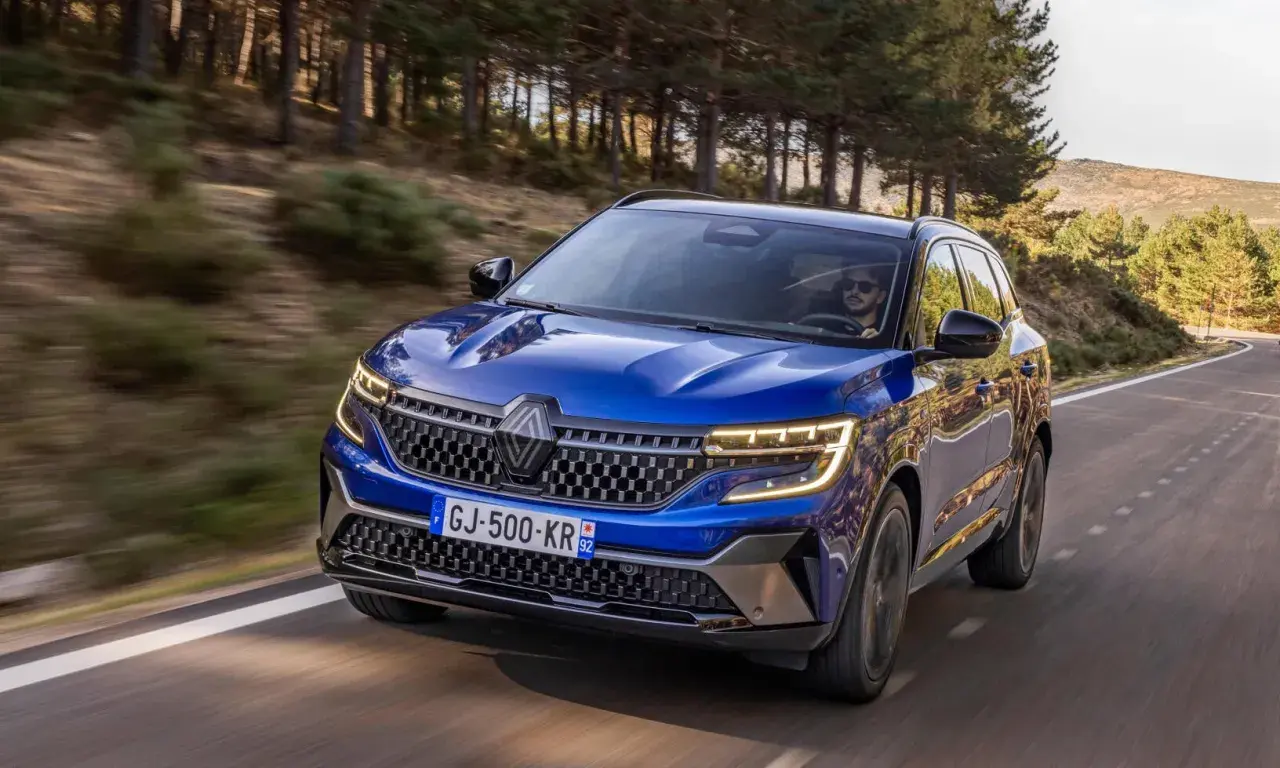 Blå Renault Austral kör på en slingrande väg genom en skog. Inga problem med denna bil, bara ren körglädje.