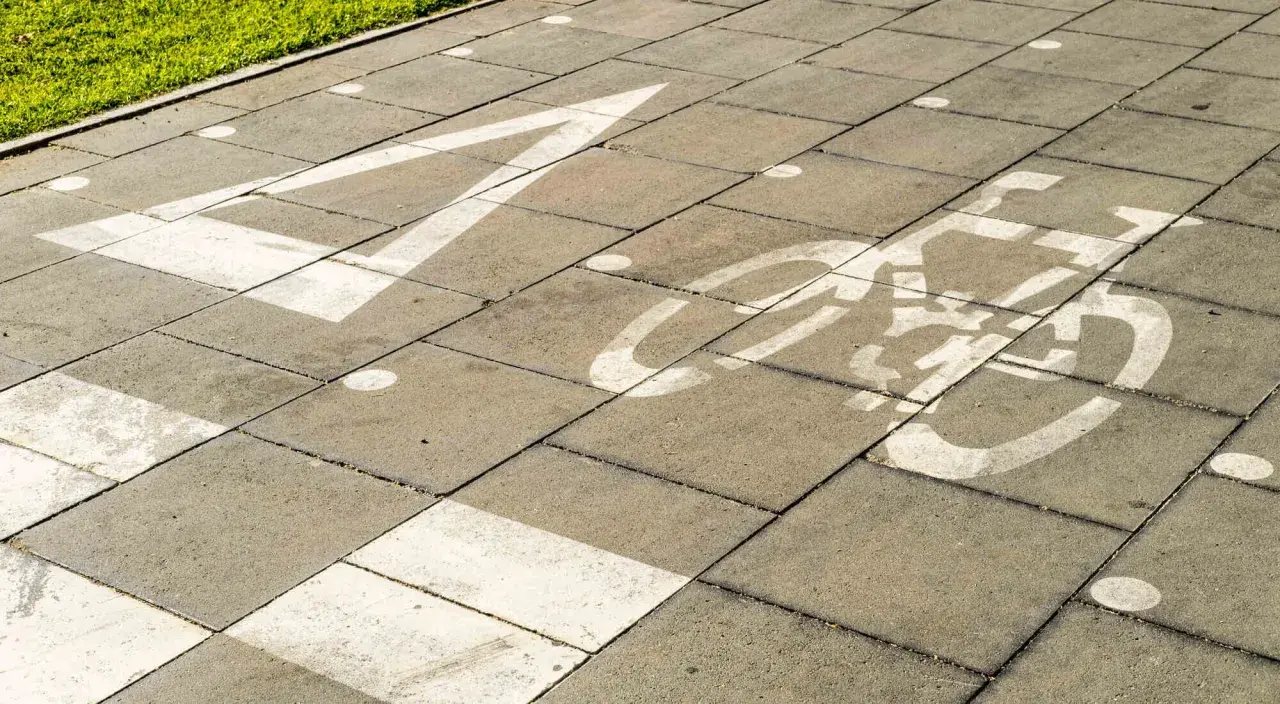 Un carril bici pintado sobre un **damero carretera** de baldosas grises. Una flecha blanca indica la dirección, seguida por el símbolo de una bicicleta.
