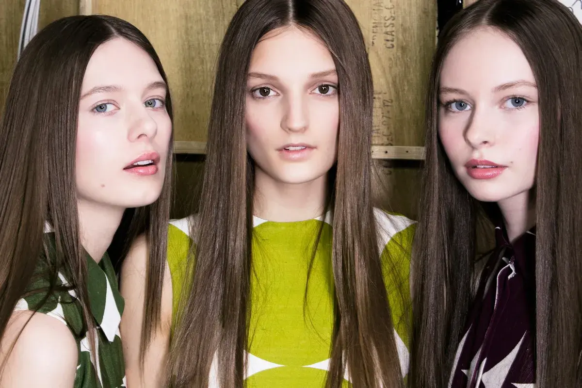 Trzy modelki z długimi włosami, prosto obciętymi, prezentują nowy trend fryzur.