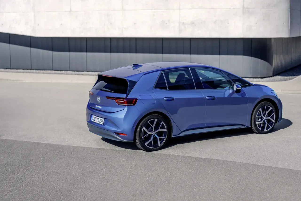 Niebieski Volkswagen ID.3 Neo stoi na tle nowoczesnego budynku.