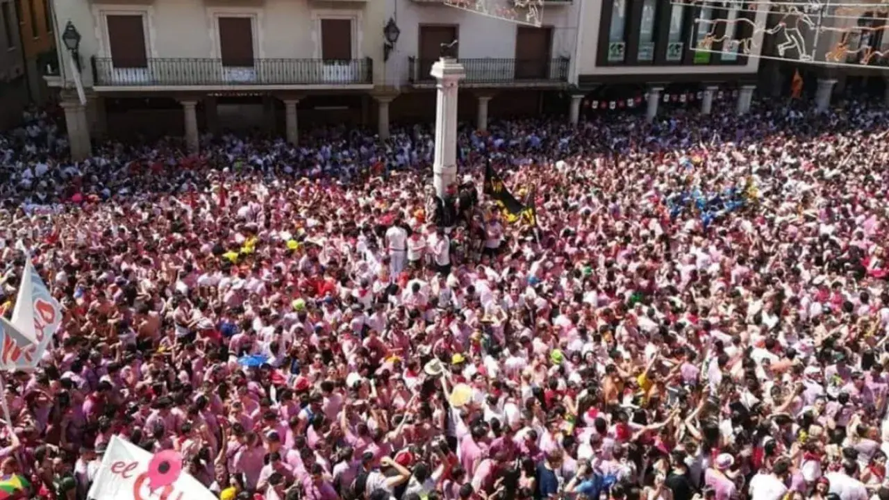 Multitudinaria plaza en las fiestas del Torico de Teruel, con gente vestida de blanco y rosa celebrando.