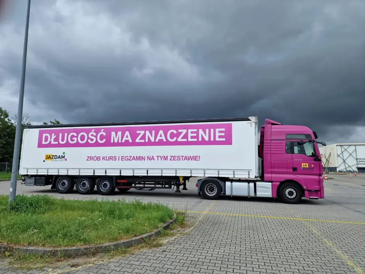 Różowy ciągnik z naczepą, na której widnieje napis "DŁUGOŚĆ MA ZNACZENIE". Idealny do nauki manewrów z dopuszczalną masą całkowitą zespołu pojazdów c+e.