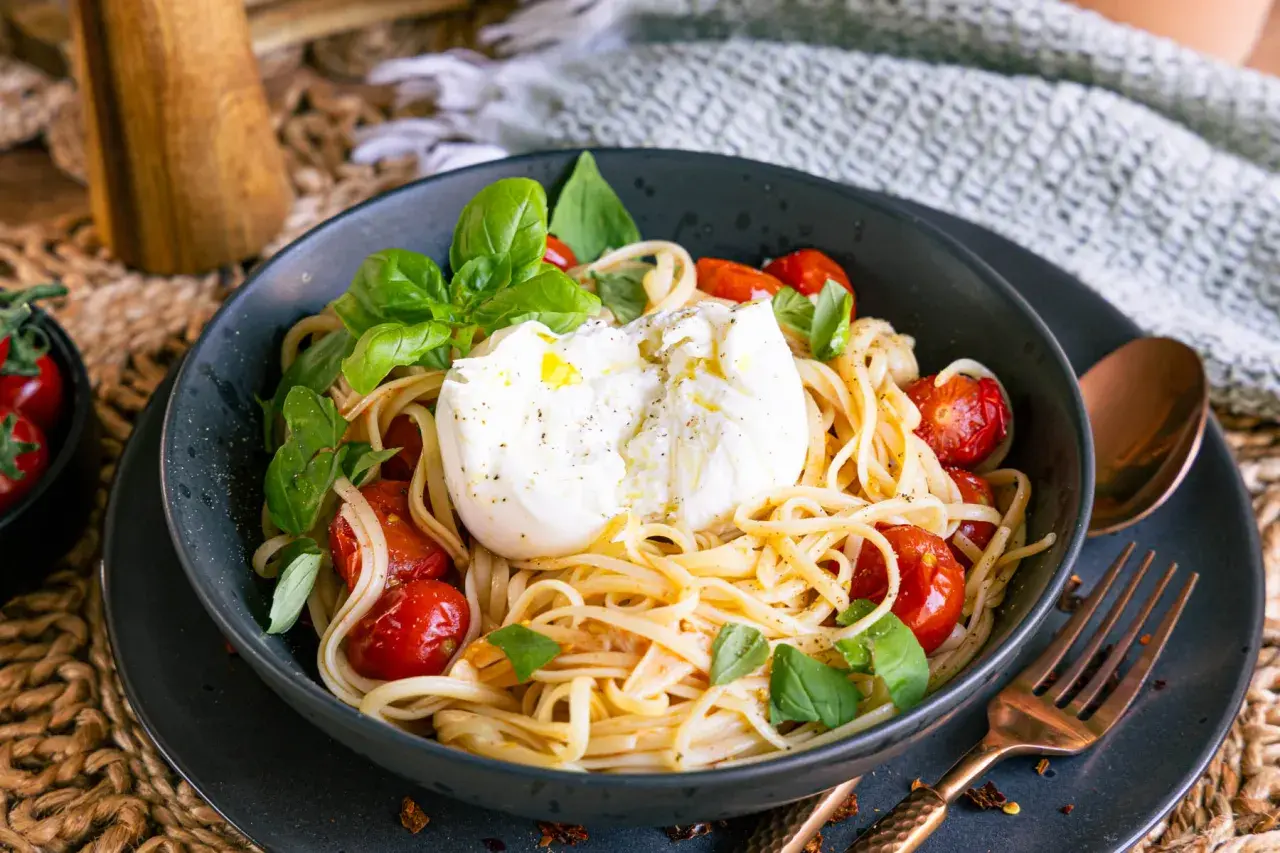 Spaghetti mit Burrata, Kirschtomaten und Basilikum in einer Schüssel.