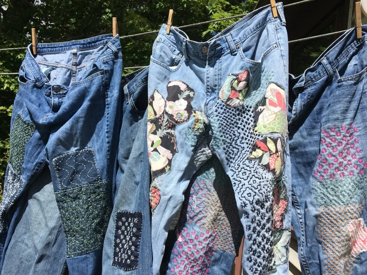Jeans repaired with colorful patches and intricate stitching, showcasing creative ways how to darn.