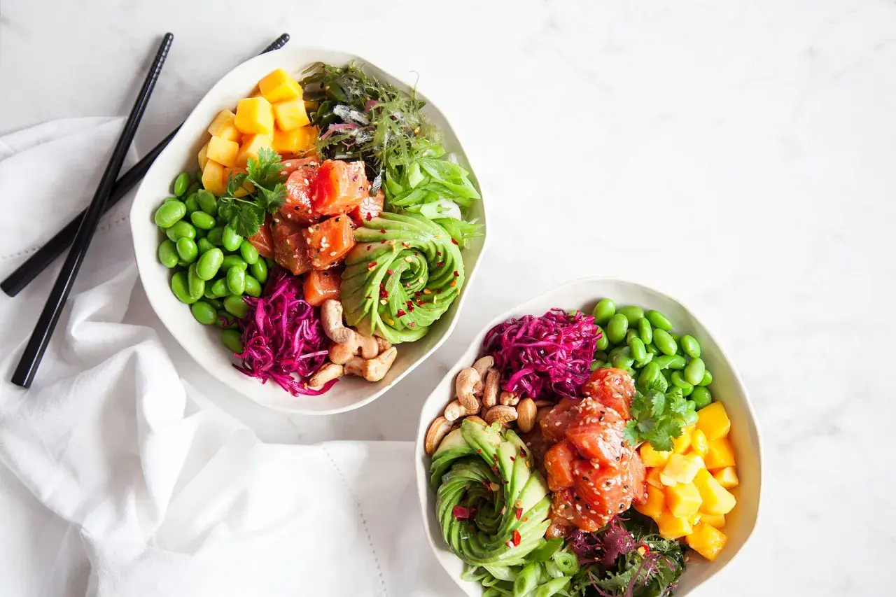 Två färgglada bowls med lax, avokado, mango, edamame och rödkål. Perfekt för en hälsosam lunch eller middag, inspirerade av bowls recept.
