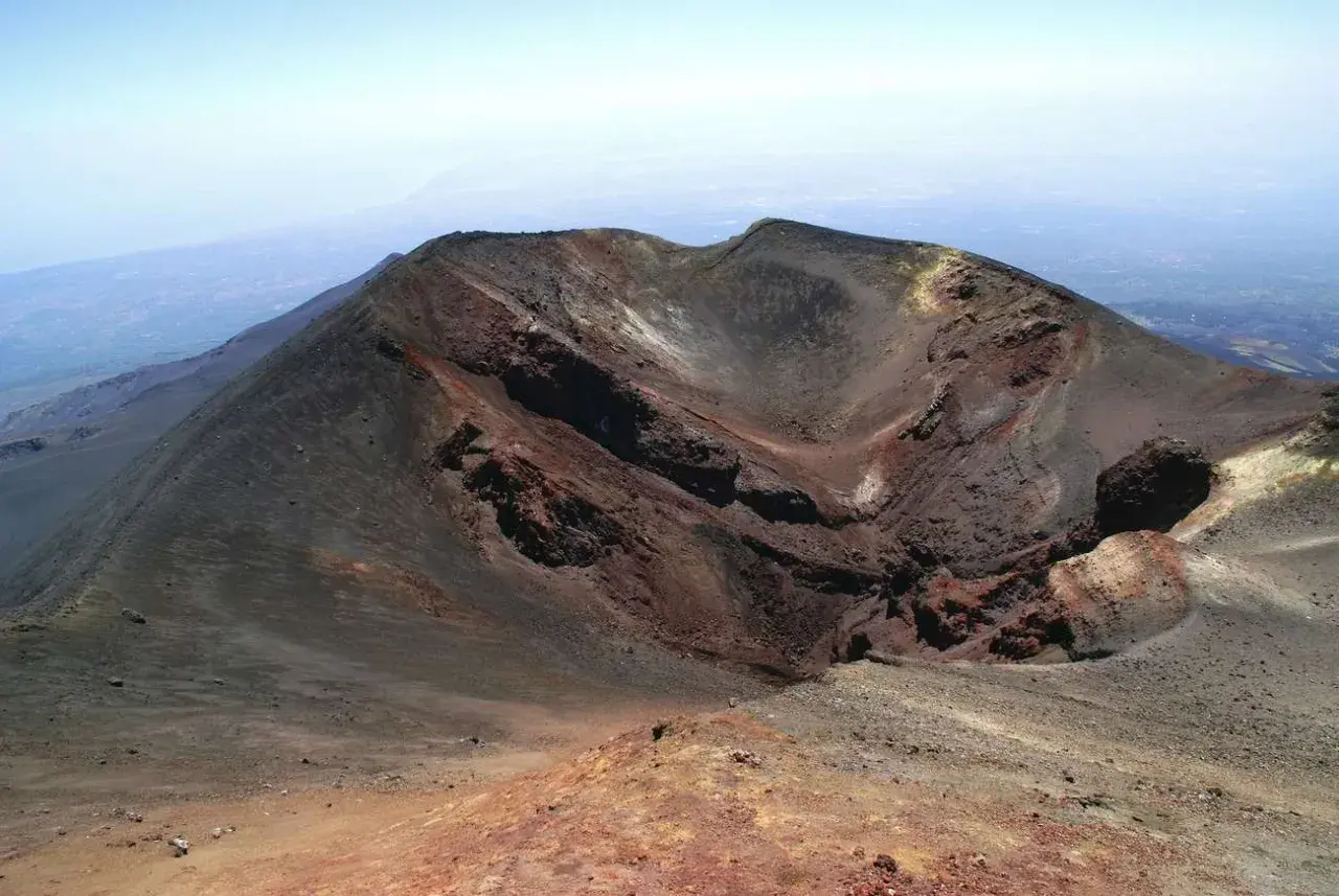 Crateri dell'Etna, un paesaggio lunare da esplorare con la propria auto. Rocce vulcaniche rosse e nere sotto un cielo azzurro.